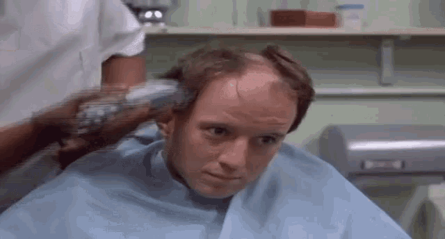 a man is getting his hair cut in a barber shop .
