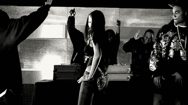 a group of people are dancing in a black and white photo and one of them is wearing a shirt that says t.