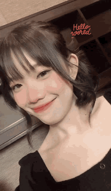 a girl is smiling with a hello world sticker on her face