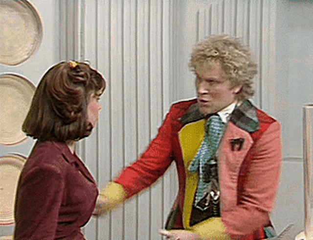 a man in a red jacket is talking to a woman in a burgundy suit