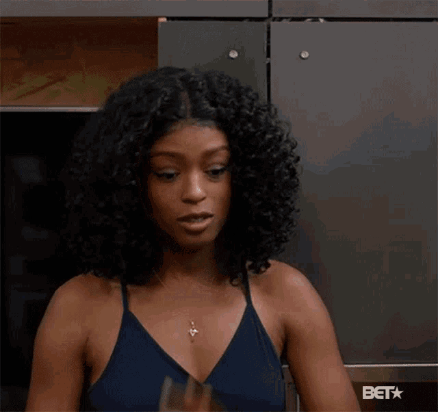 a woman with curly hair is standing in front of a wall that says beta on it
