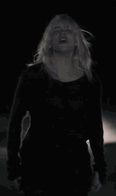 a woman with blonde hair screaming in the dark