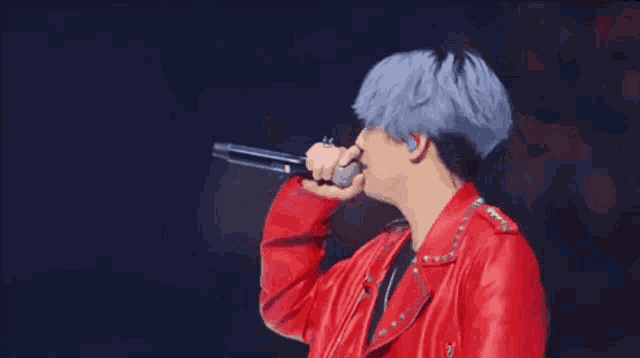 a man in a red jacket is holding a microphone in his hand .