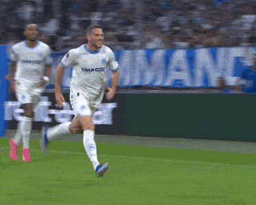 a soccer player wearing a white shirt that says emaco is running on the field