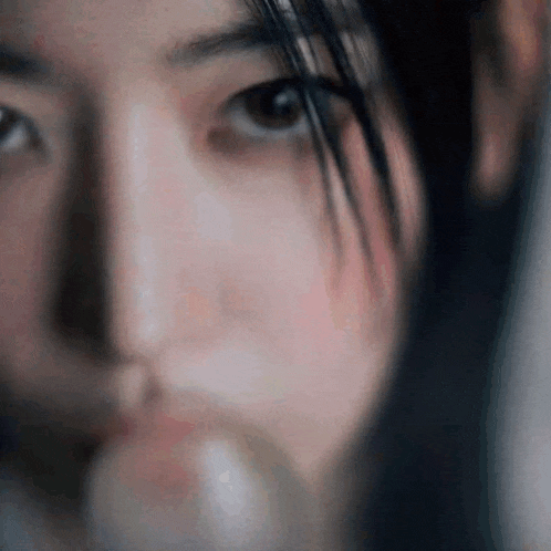 a close up of a woman 's face with a glass of water in her hand .