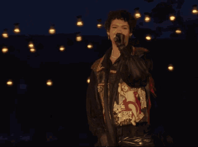 a woman singing into a microphone while wearing a black jacket