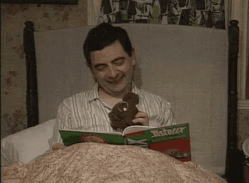 a man is reading a book called asterix and holding a teddy bear