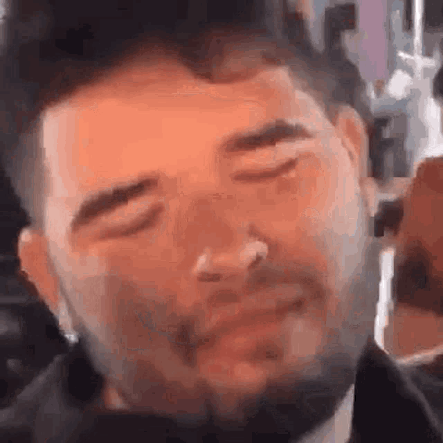 a close up of a man 's face with his eyes closed and a beard .
