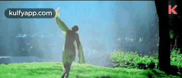 a person is standing in the grass with their arms outstretched in a field .
