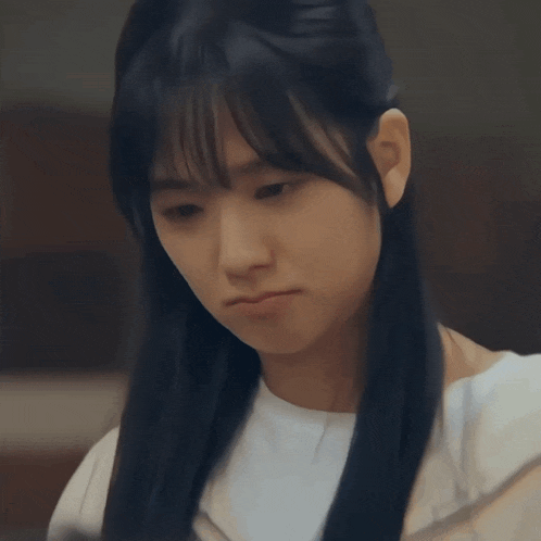 a woman with long black hair and bangs is looking down