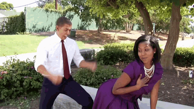 a man and a woman are dancing in a park