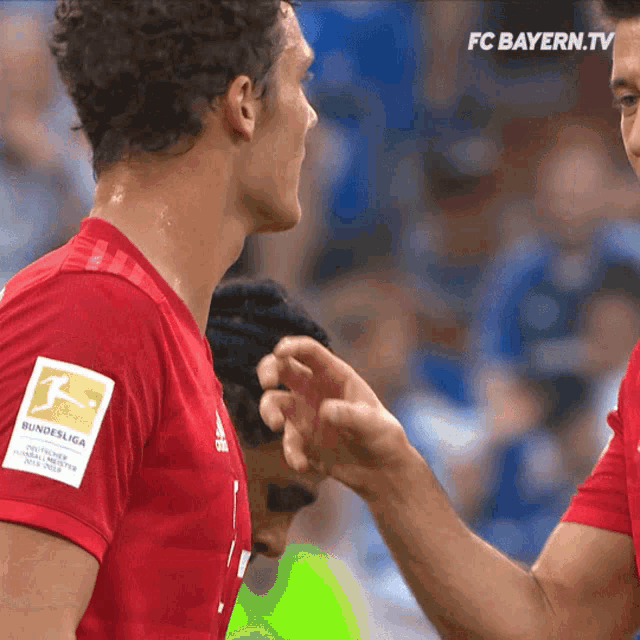 two soccer players shake hands in front of a screen that says fc bayern