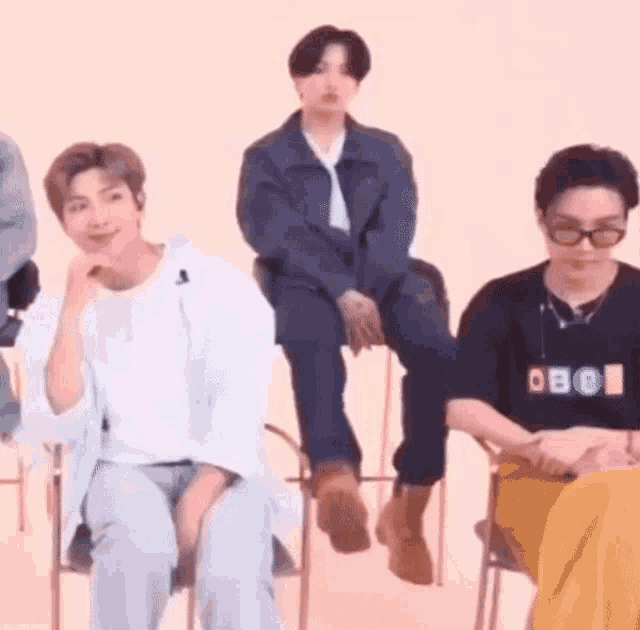 a group of young men are sitting on chairs and talking to each other .