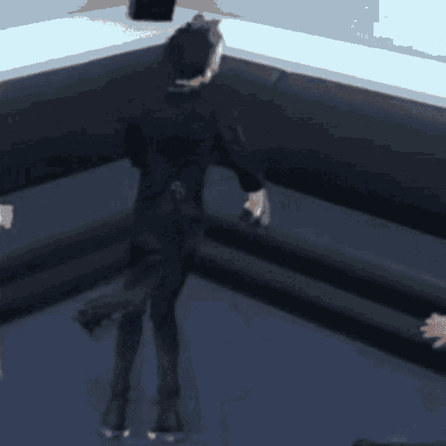 a man in a black suit is dancing in a room with a couch
