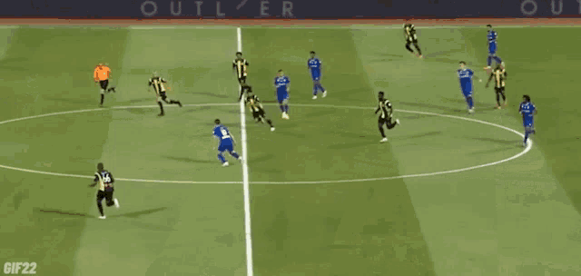 a group of soccer players are playing on a field with an outlier advertisement in the background