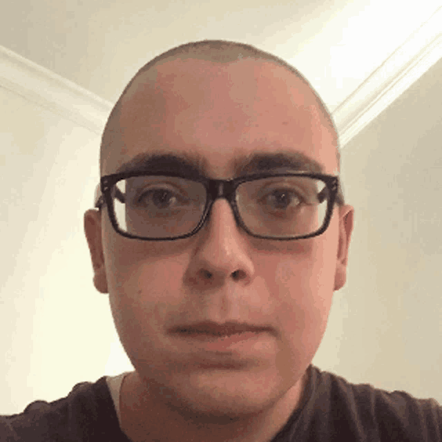 a man with glasses and a bald head looks at the camera