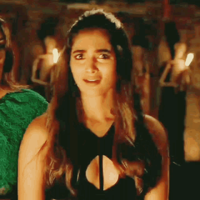 a woman in a black top with a plunging neckline is making a funny face