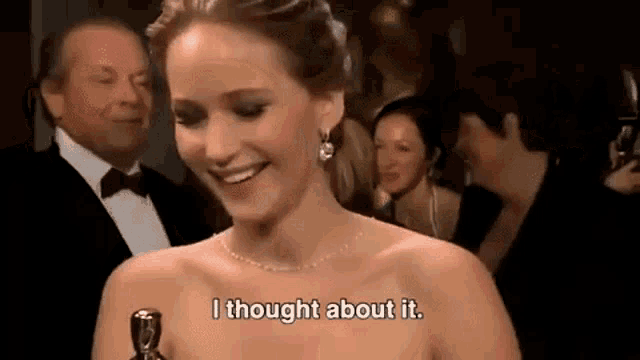 a woman is smiling while holding an oscar statue and says `` i thought about it . ''