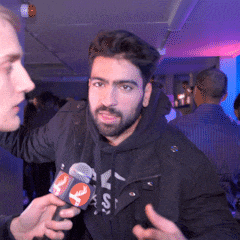 a man in a black jacket is being interviewed by another man while holding a microphone