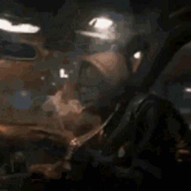 a man is smoking a cigarette while sitting in a car at night .