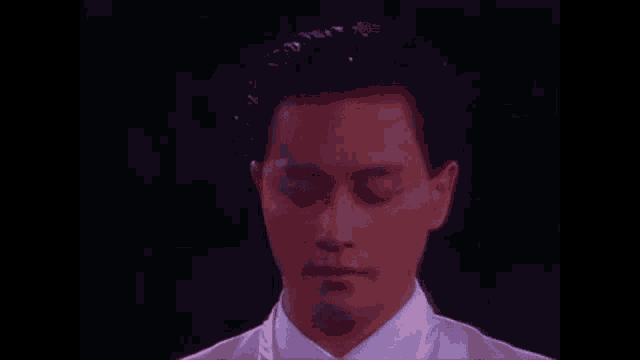 a man in a white shirt and tie is standing in front of a black background .