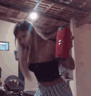 a woman is dancing in a room while holding a red speaker