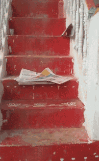 a red staircase with a newspaper on the bottom steps