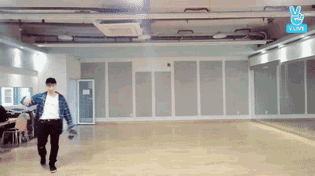 a man is dancing in an empty room with a sign that says vlive .