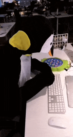 a person in a penguin costume is sitting at a desk