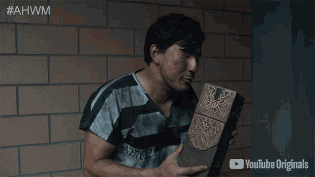 a man in a striped shirt is holding a box with youtube originals written on it