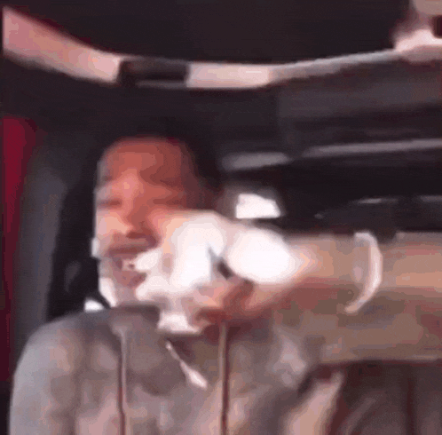 a man is sitting in a car with his face taped to the roof .