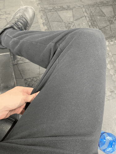 a person wearing black pants is sitting on a bench
