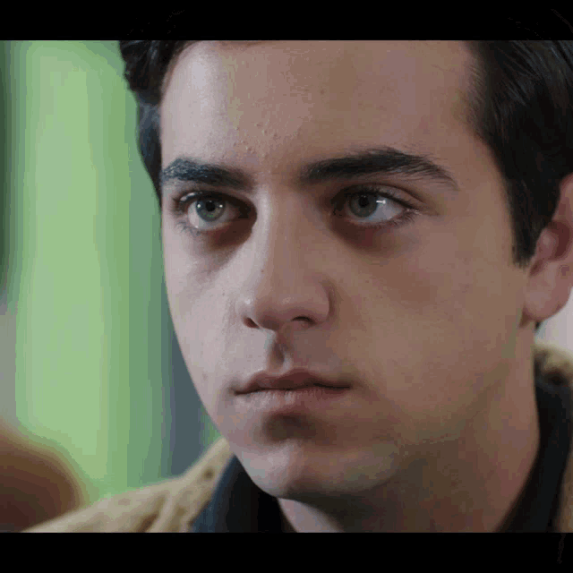 a close up of a young man 's face with a green eye