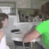 a man in a green shirt is standing next to a woman in a white tank top in a kitchen .