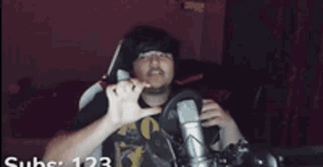 a man is sitting in front of a microphone with his hands on his head .