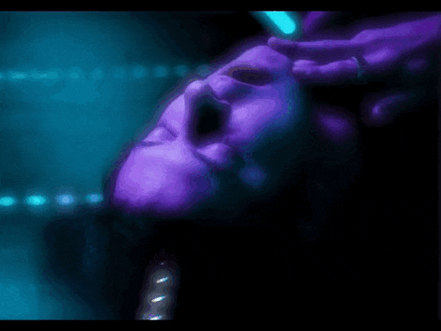 a close up of a person 's face with purple and blue lights behind them