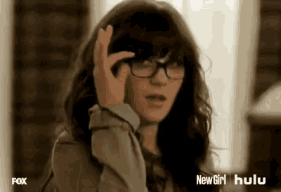 a woman wearing glasses is talking on a cell phone and making a funny face .