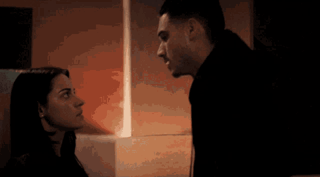 a man and a woman are looking at each other in the dark