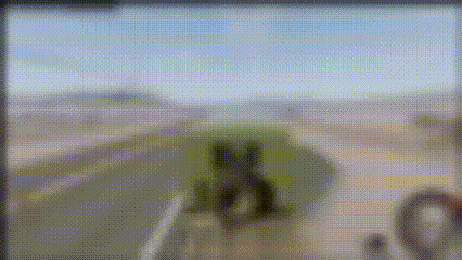 a blurred image of a person standing on a beach with a green object in the foreground .