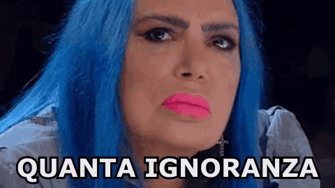 a woman with blue hair and pink lipstick has the words quanta ignoranza written on her face .