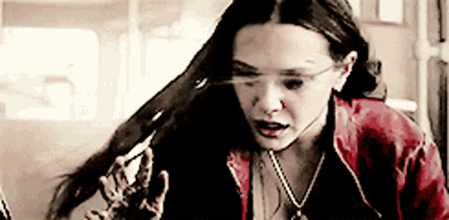 a woman with long hair is wearing a red jacket and necklace
