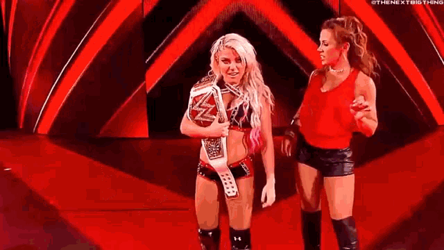 two female wrestlers are standing next to each other on a stage .