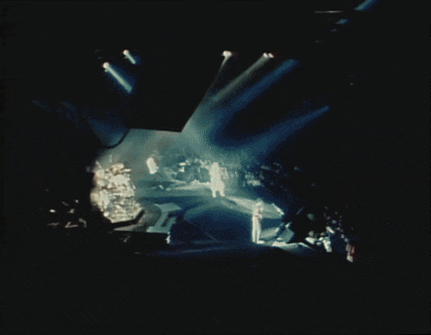 a blurred image of a concert with a crowd watching