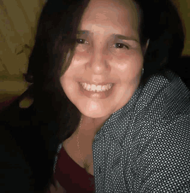 a woman wearing a plaid shirt and a red top smiles for the camera