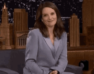 a woman in a suit is sitting on a couch