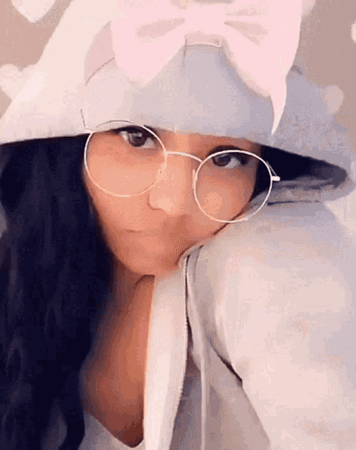 a woman wearing glasses and a hat with a bow