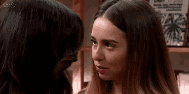 two women are looking at each other and touching their foreheads .