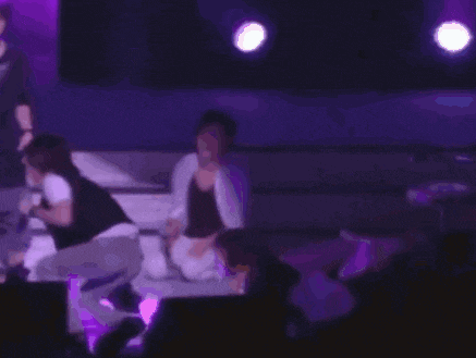 a group of people on a stage with purple lights