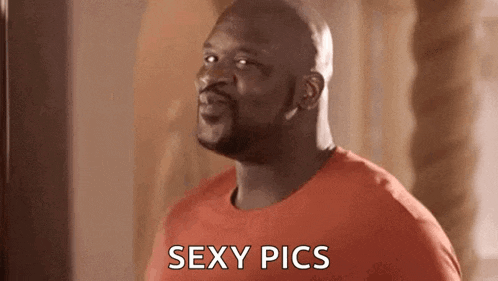 a bald man in a red shirt is standing in front of a mirror and says `` sexy pics '' .