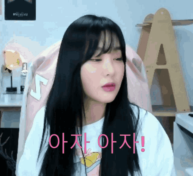 a girl with long black hair is sitting in a pink chair with the letters s on it